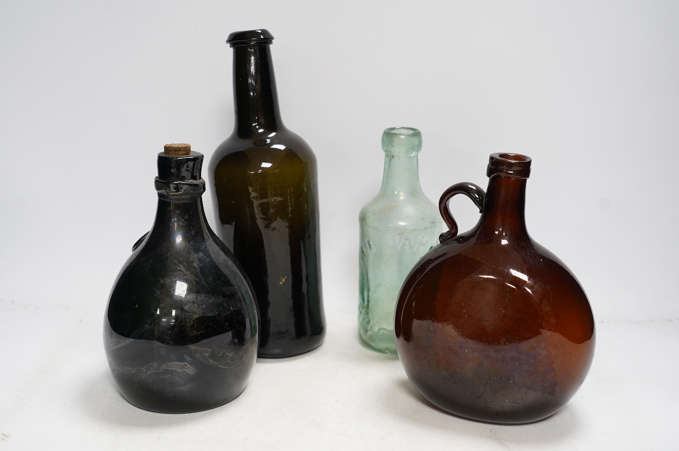 A Georgian wine bottle and three others including one bearing label reading ‘J.G. MONNET & Co. COGNAC’, tallest 27cm. Condition - commensurate with age